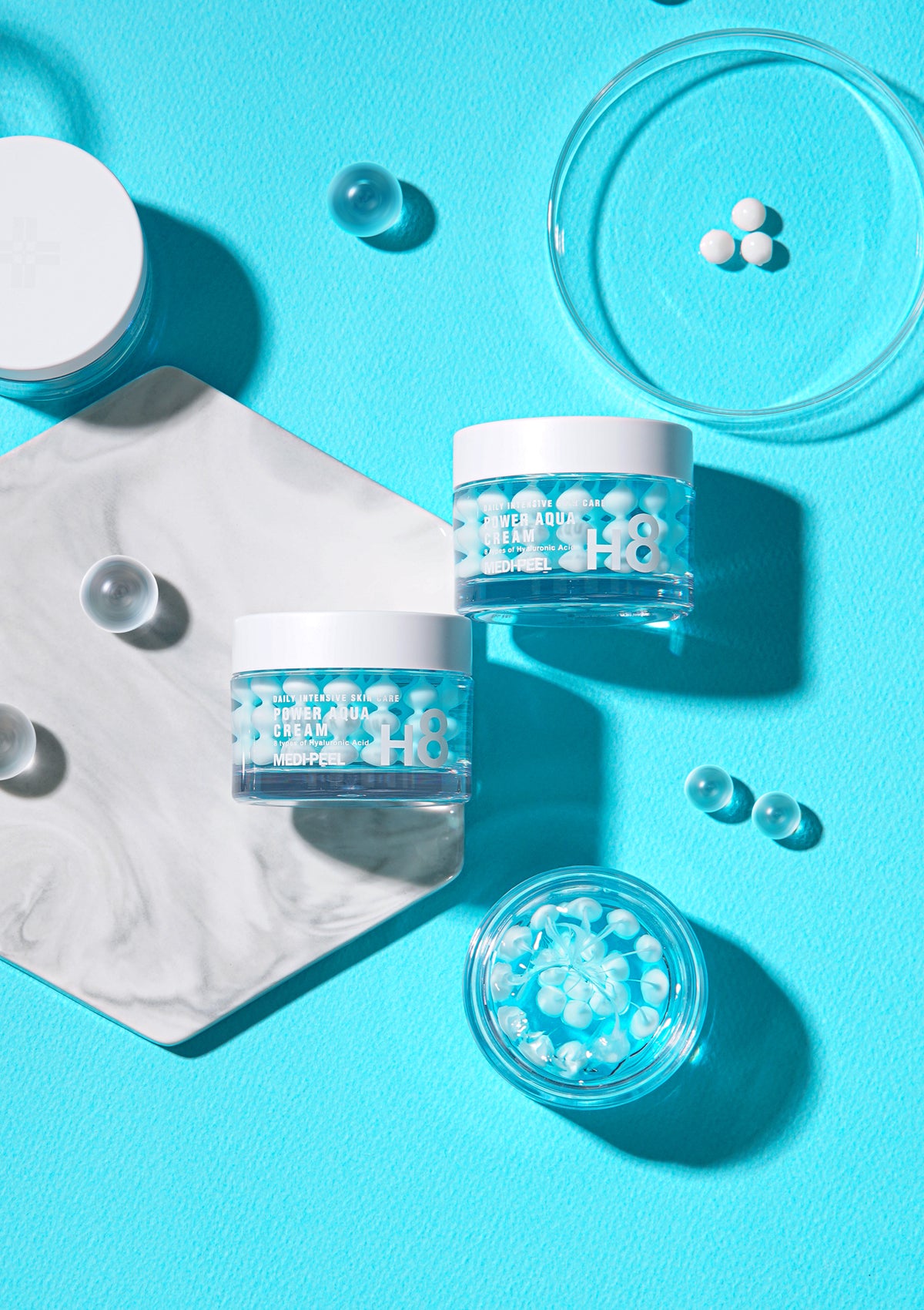 Four different variants of MEDIPEEL Drop Capsule Gel Creams, each in their own container with labels indicating their specific benefits such as Anti-Aging, Brightening, Soothing, and Hydration.